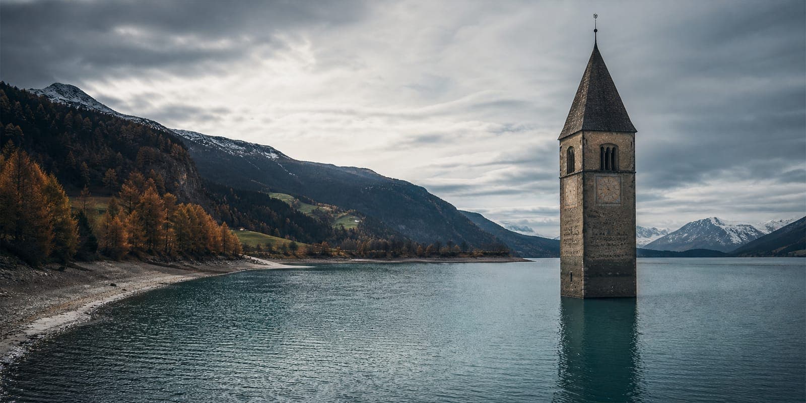 Reschensee im Vinschgau mit versunkenem Kirchturm und weitem Berglicht